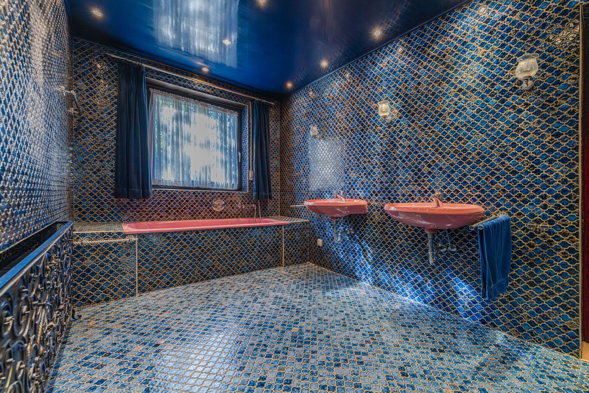 Badezimmer mit blauen Fliesen, zwei rosa Waschbecken und einer rosa Badewanne.