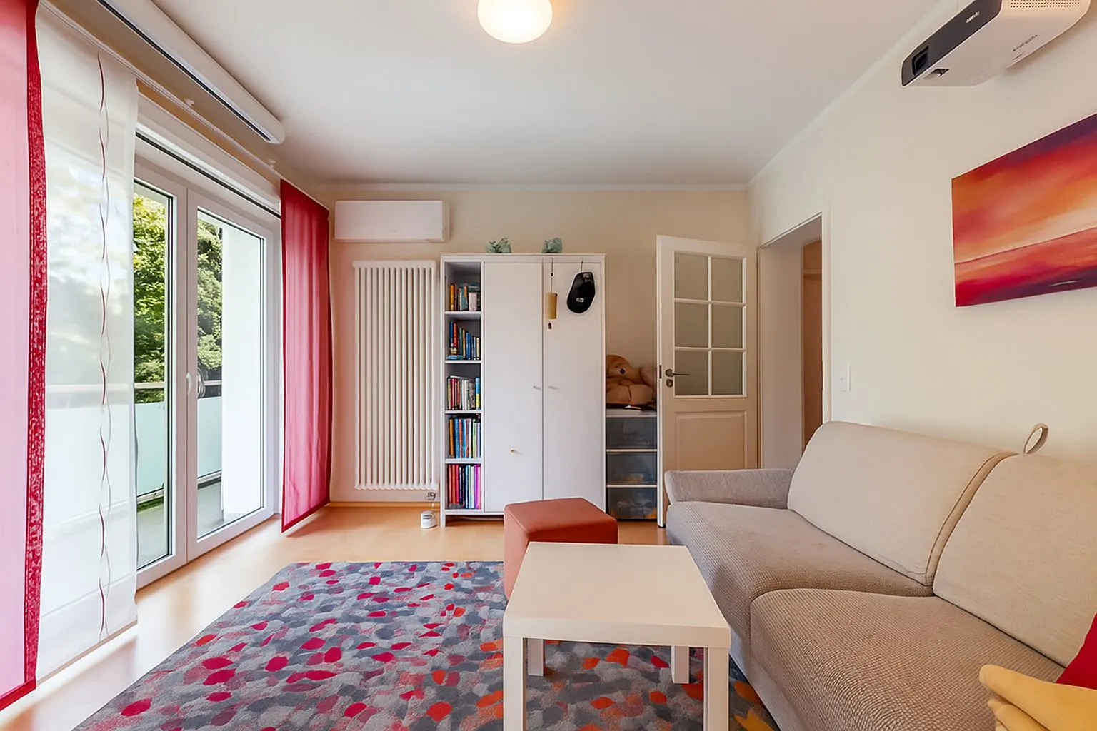 Helles Wohnzimmer mit Sofa, Couchtisch, Regal und Zugang zu einem Balkon.