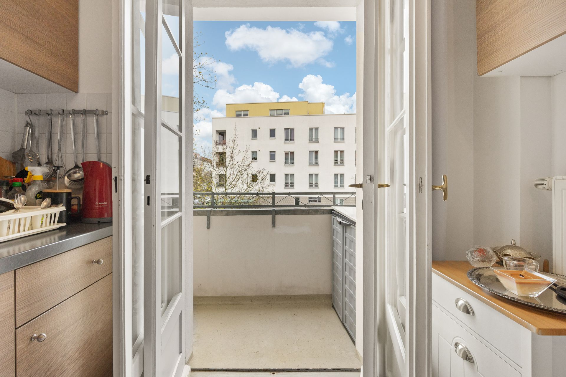 Blick aus einer Küche auf einen kleinen Balkon und ein Wohngebäude gegenüber.