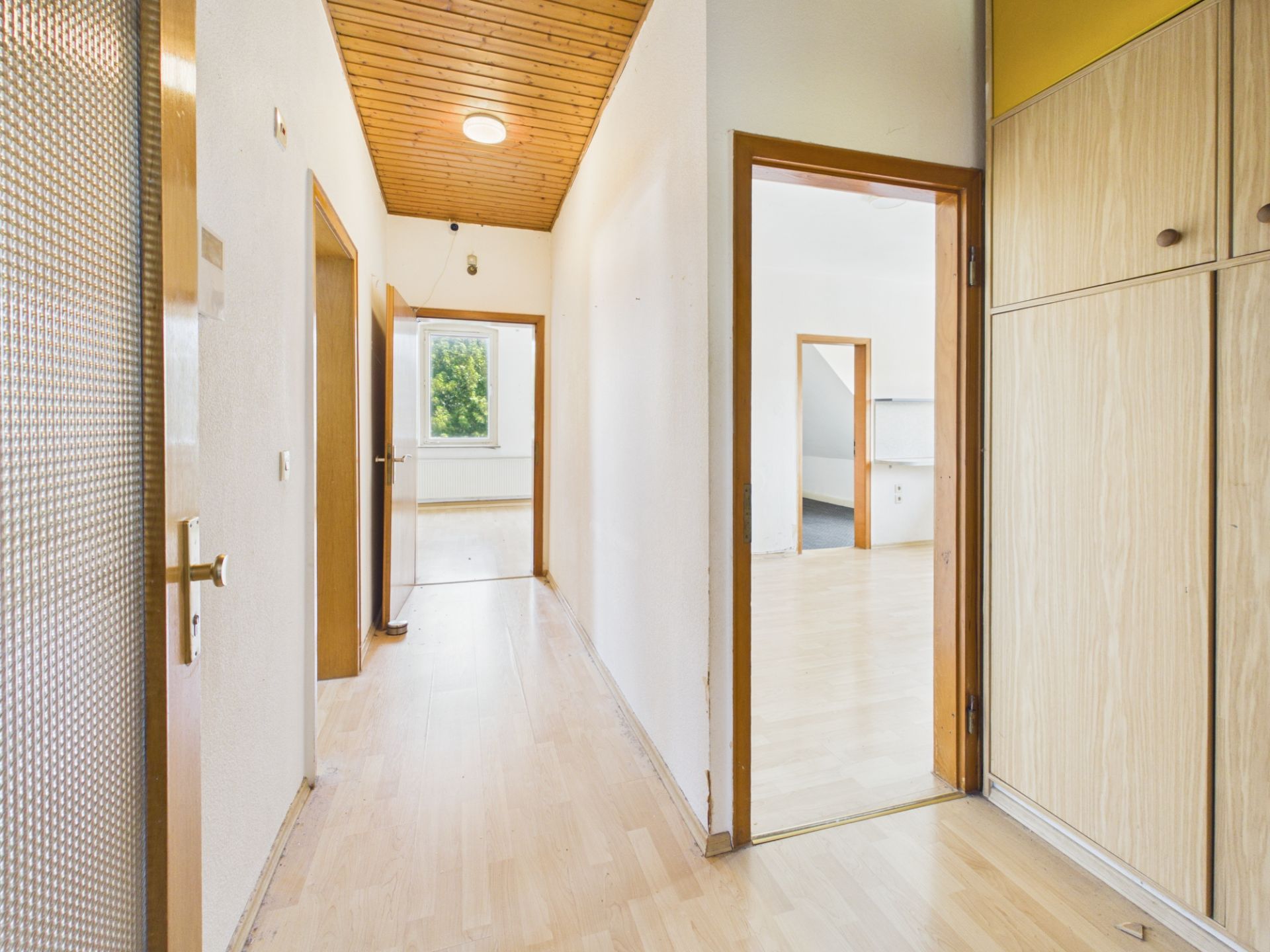 Heller Flur mit Holzboden, Türen zu mehreren Zimmern und Einbauschrank rechts.