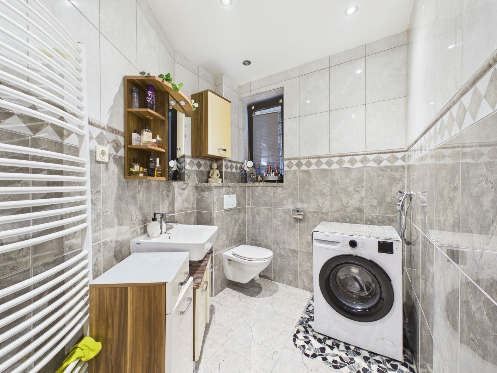 Modernes Badezimmer mit Waschmaschine, Wandtoilette, Waschbecken und Regalen.