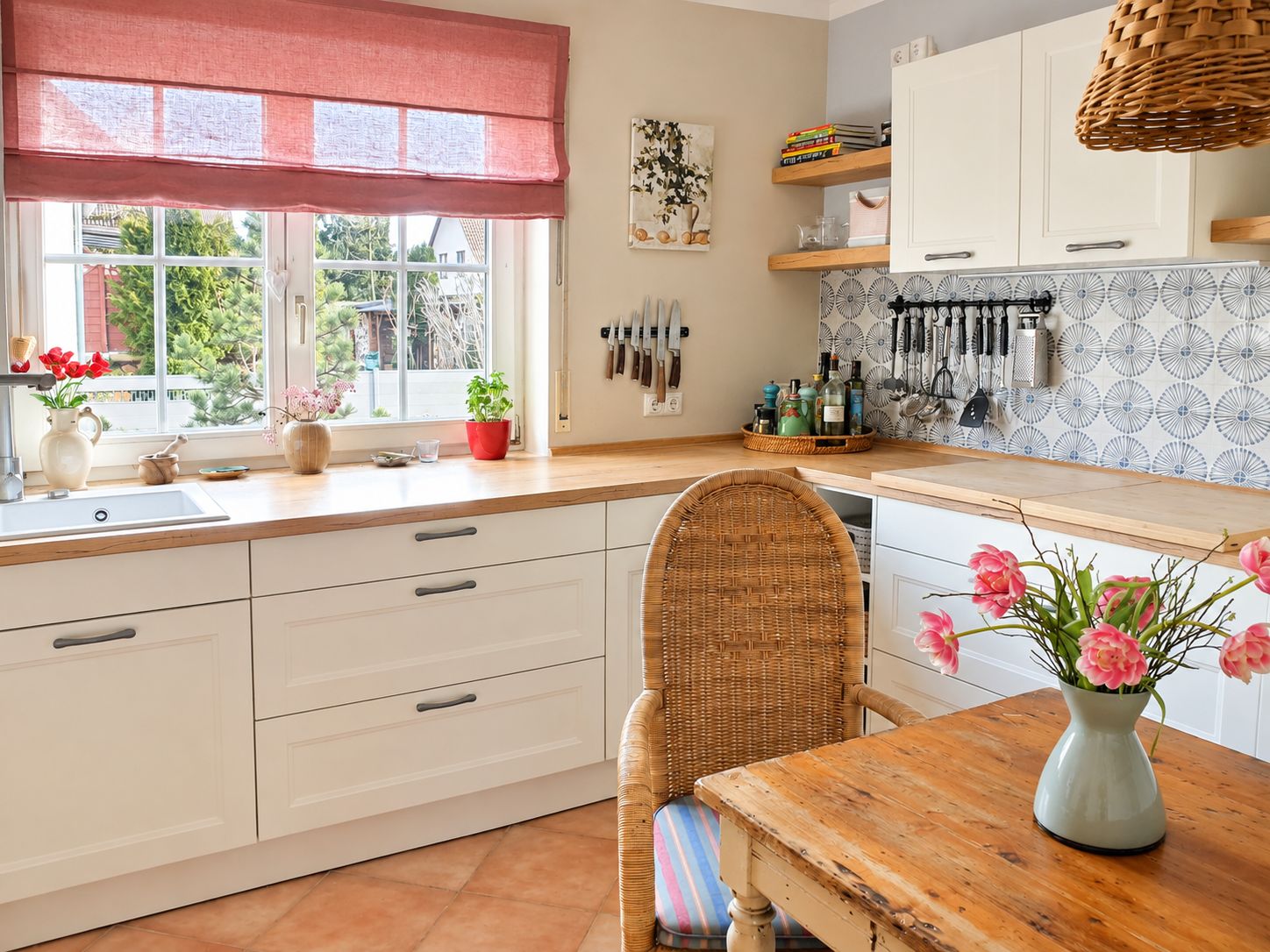 Helle Küche mit Holzarbeitsplatten, weißen Schränken und einem Holztisch mit Blumenvasen.
