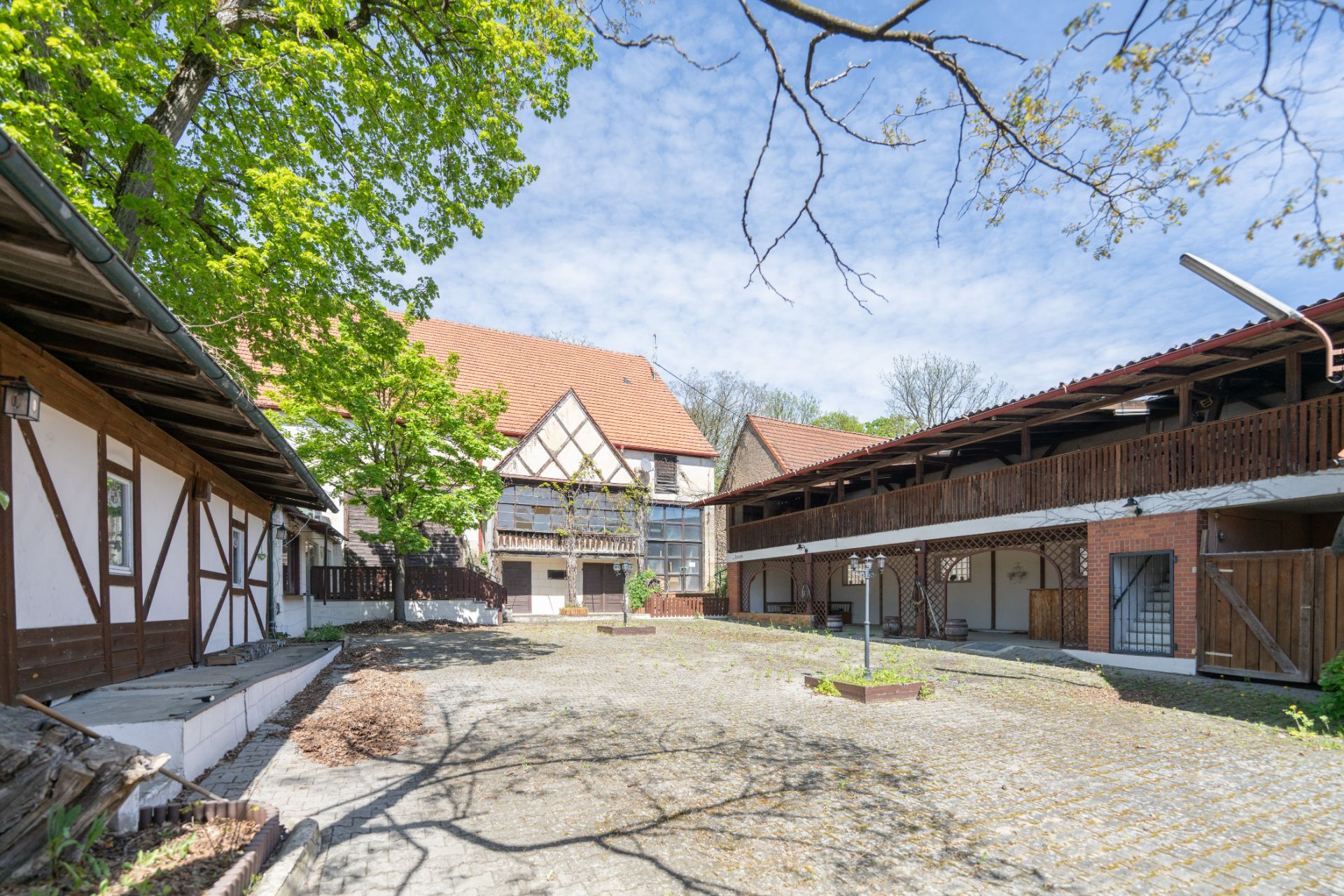 Gepflasterter Innenhof mit Fachwerkhäusern und Bäumen bei sonnigem Wetter.
