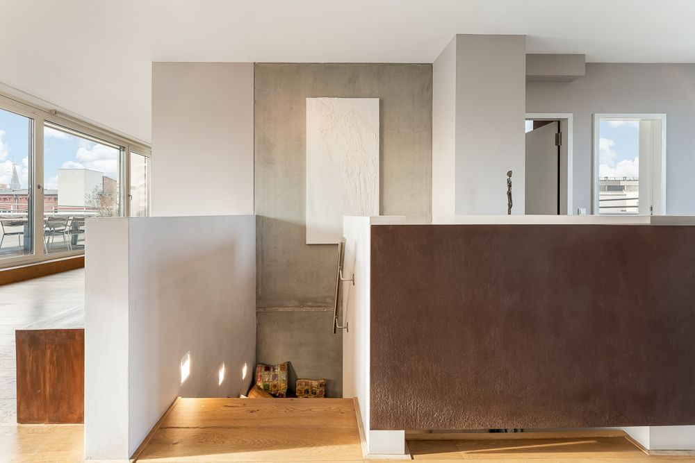 Helle Treppenhausansicht mit modernen Wänden und großem Fenster im Wohnbereich.