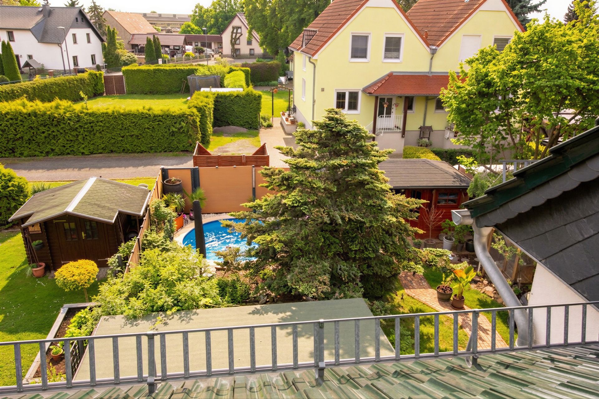 Blick von oben auf einen Garten mit Pool, Gartenhaus und angrenzendem Wohnhaus.