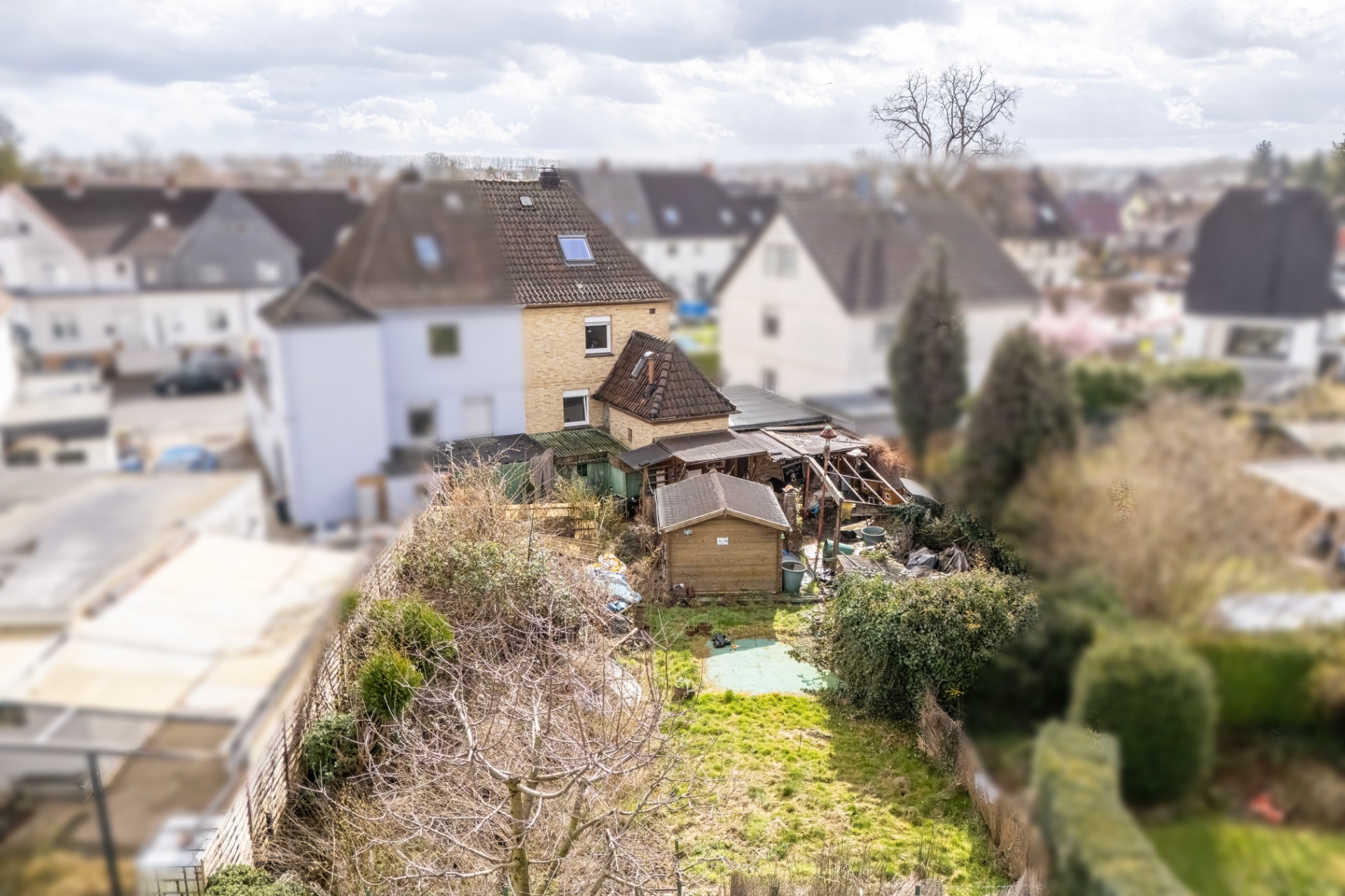 Blick auf einen Garten mit Rasenfläche und Schuppen hinter einem Wohnhaus.