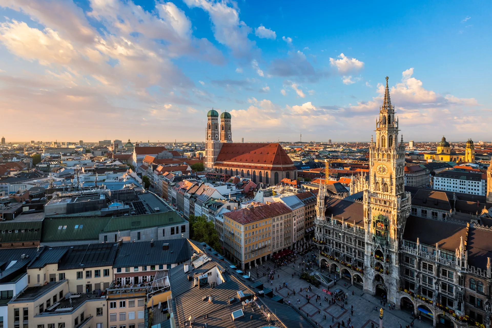 Blick über eine Stadt mit historischen Gebäuden, Kirchtürmen und Marktplatz bei Sonnenuntergang.