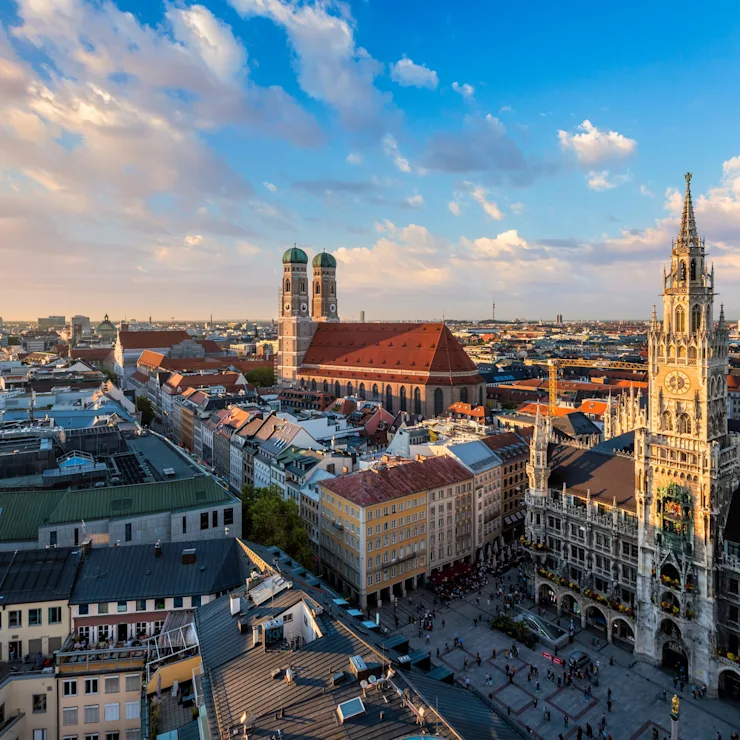 Blick über eine Stadt mit historischen Gebäuden, Kirchtürmen und Marktplatz bei Sonnenuntergang.