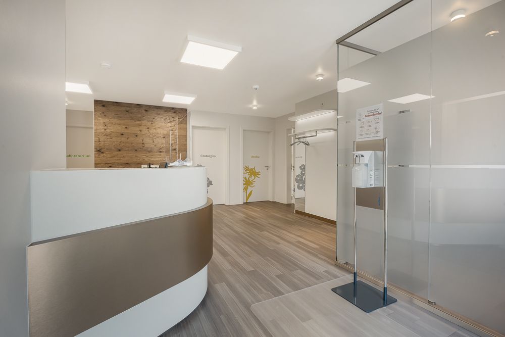 Moderner Eingangsbereich mit Empfangstresen, Holzwand und Glastrennwand.