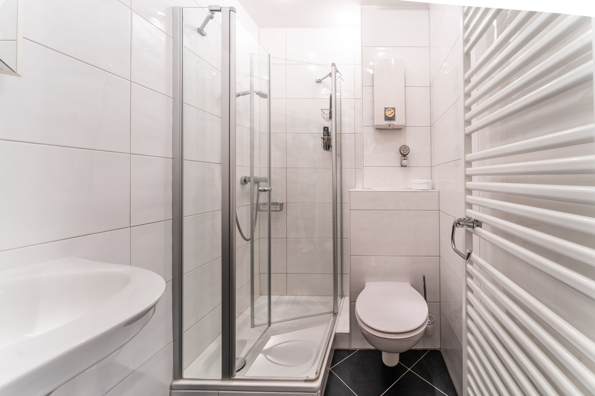 Modernes, kleines Badezimmer mit Dusche, Toilette, Waschbecken und Handtuchheizkörper.