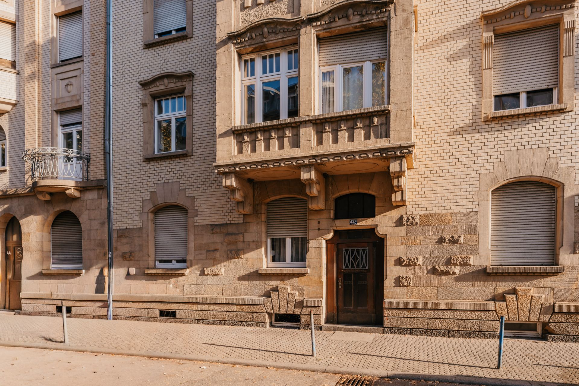 Fassade eines Wohngebäudes mit Balkonen, Fenstern und geschlossener Eingangstür.
