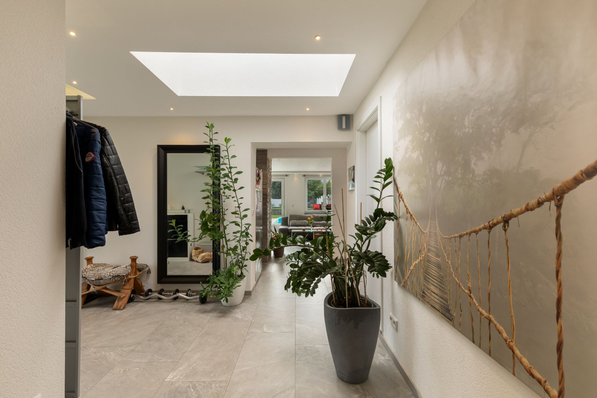 Heller Flur mit Pflanzen, Spiegel, Garderobe und großem Bild an der Wand.