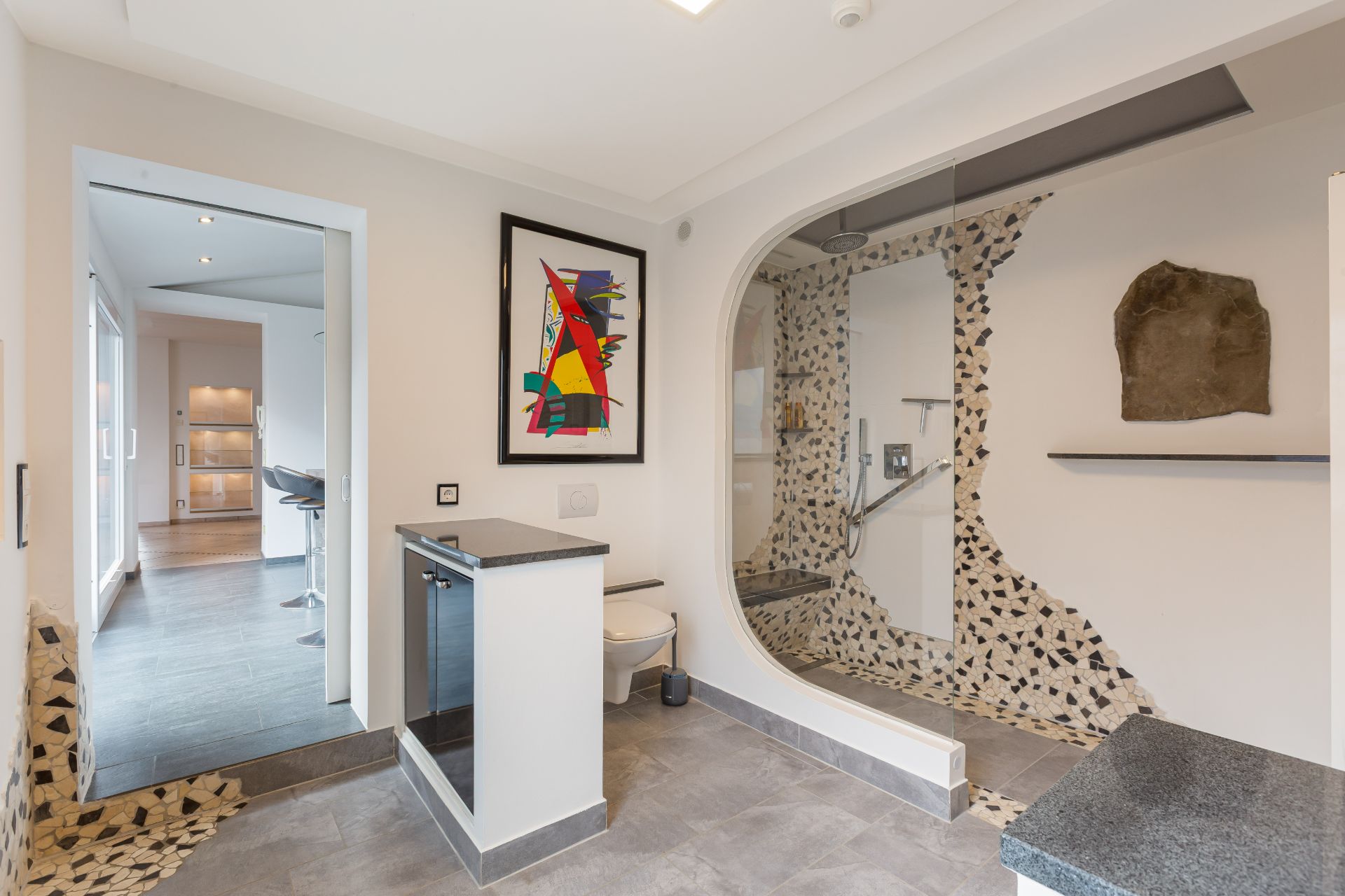 Modernes Badezimmer mit begehbarer Dusche, Kunstwerk an der Wand und Mosaikfliesen.