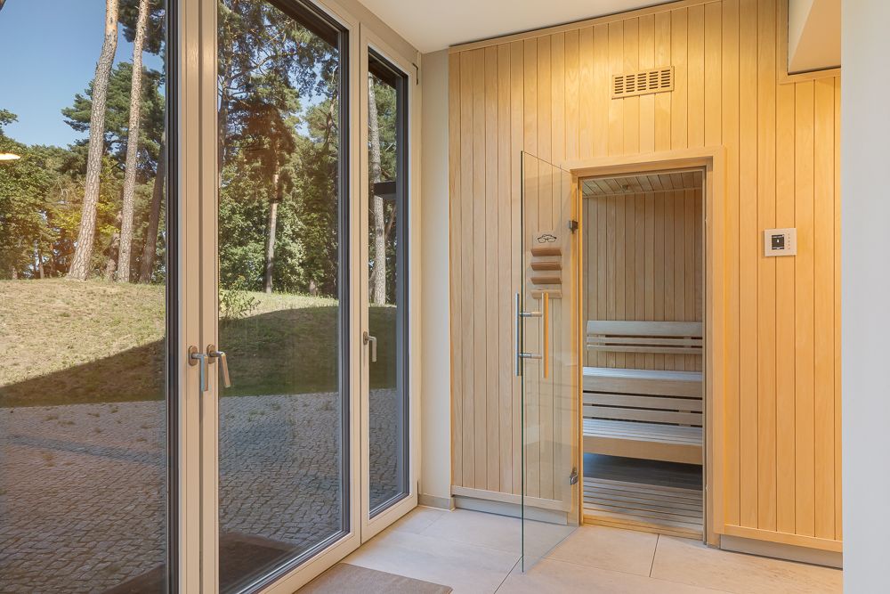 Heller Raum mit großen Fenstern und einer Sauna mit Holzwänden und Glastür.