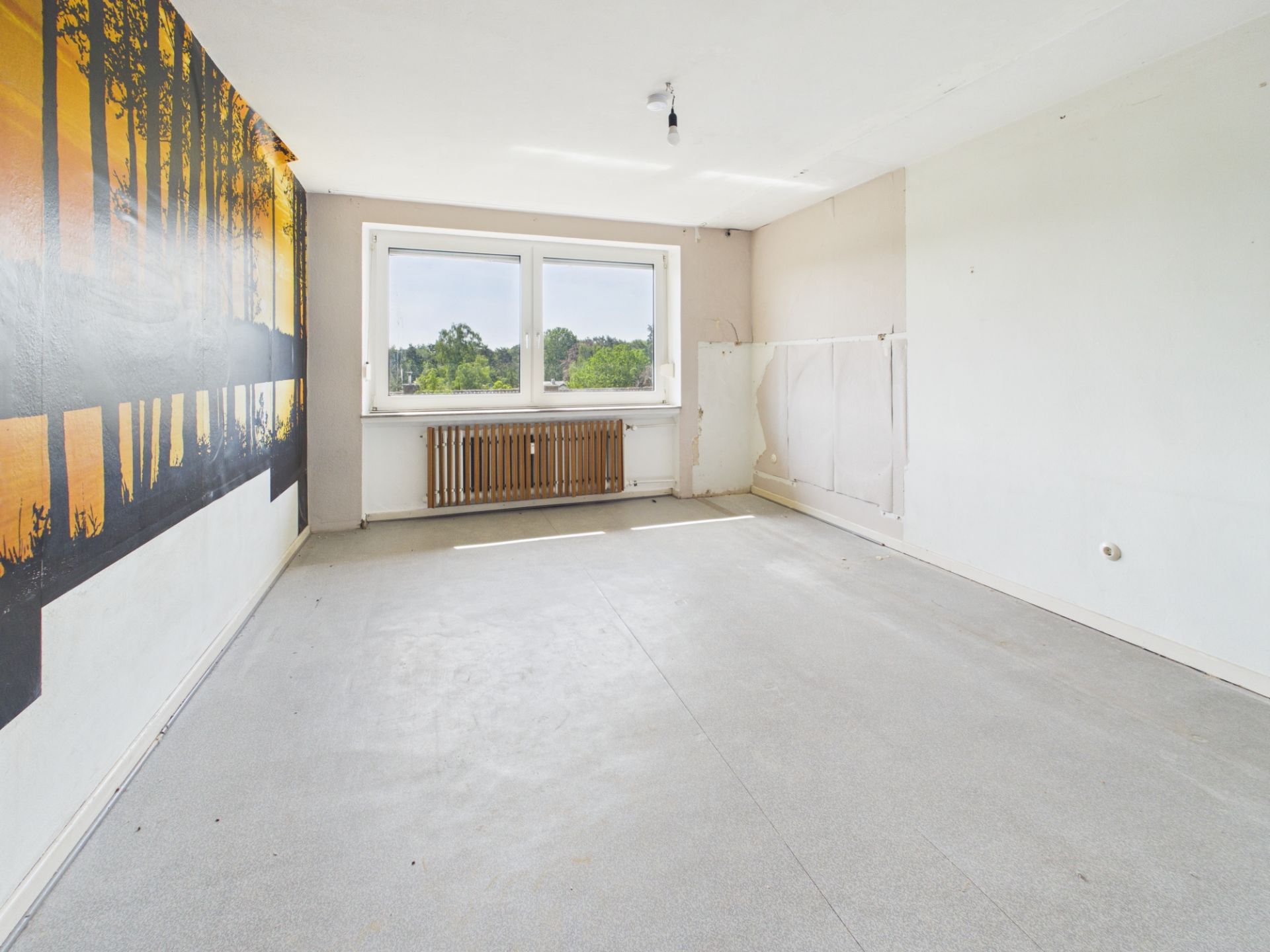 Leerer Raum mit großem Fenster, Wandbild und sichtbarem Heizkörper.