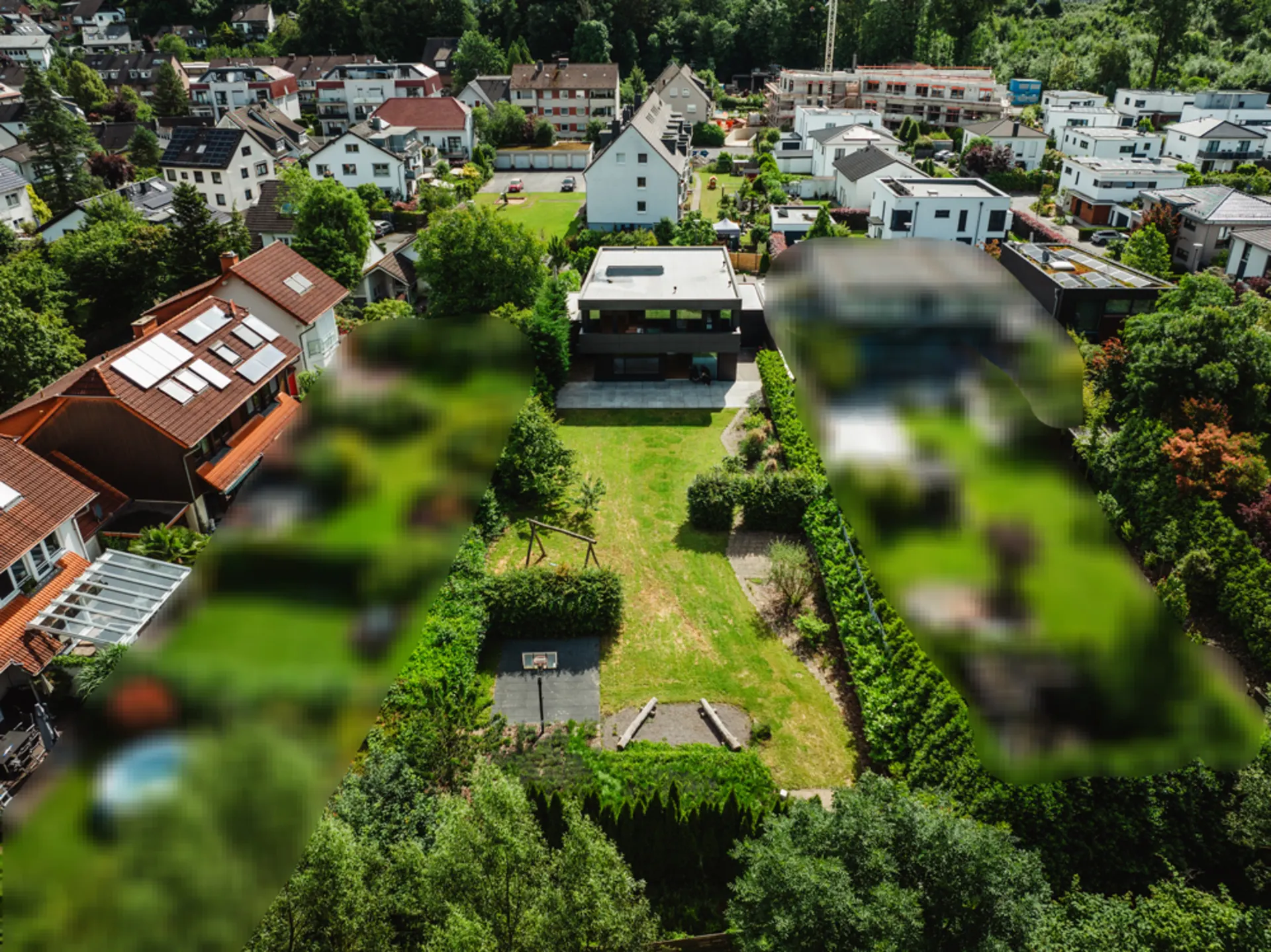 Luftaufnahme eines modernen Einfamilienhauses mit großem Garten und Basketballfeld.