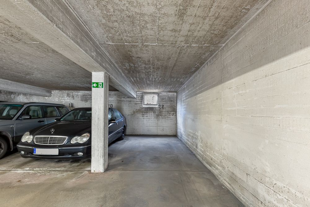 Tiefgaragenstellplätze mit zwei geparkten Autos und einem freien Platz in Betonumgebung.