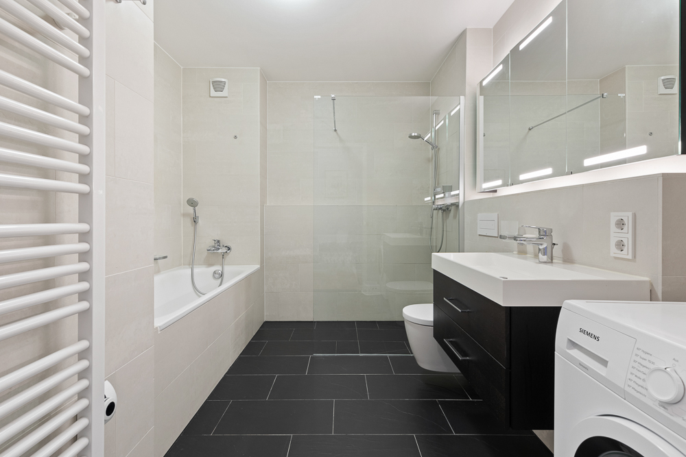 Modernes Badezimmer mit Badewanne, Dusche, Waschbecken, Toilette und Waschmaschine.
