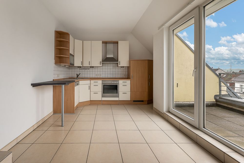 Helle Einbauküche mit Fliesenboden und großem Fenster zur Terrasse.