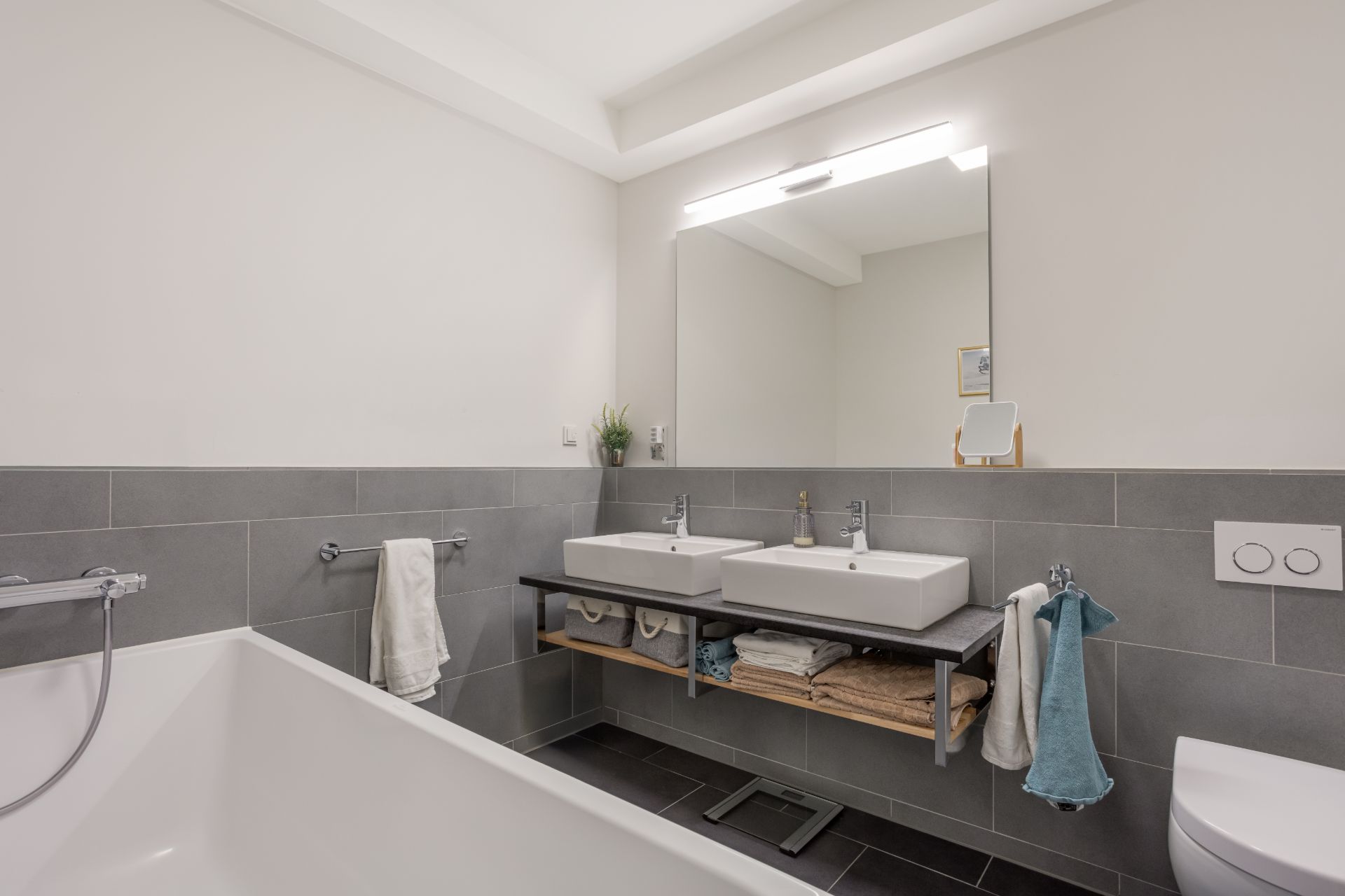Modernes Badezimmer mit Badewanne, zwei Waschbecken, Spiegel und Handtüchern.