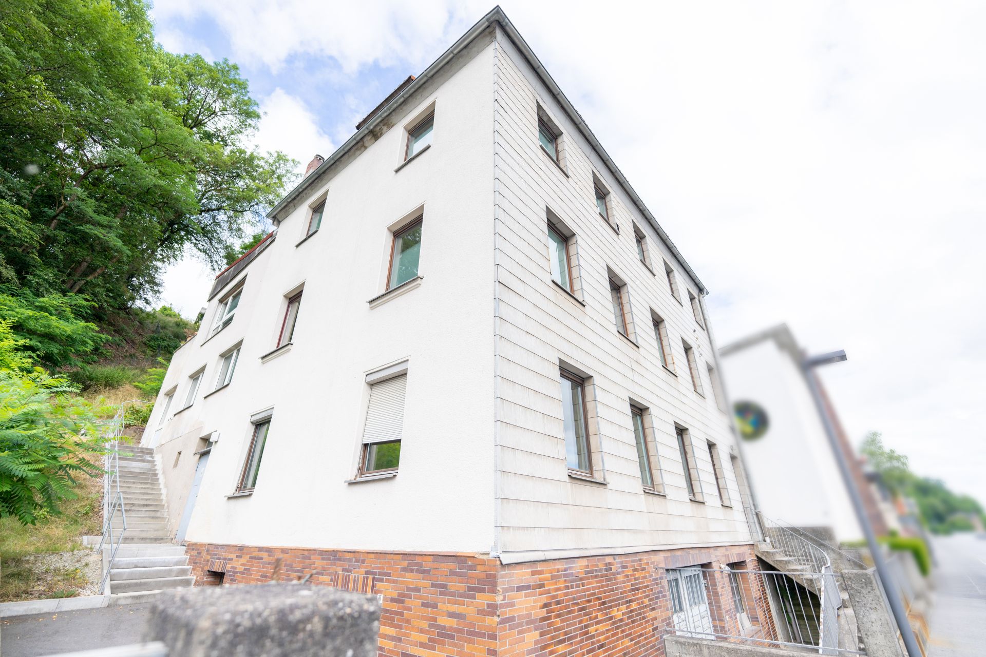 Mehrstöckiges Wohnhaus mit weißen Fassaden und vielen Fenstern, Treppe an der Seite.