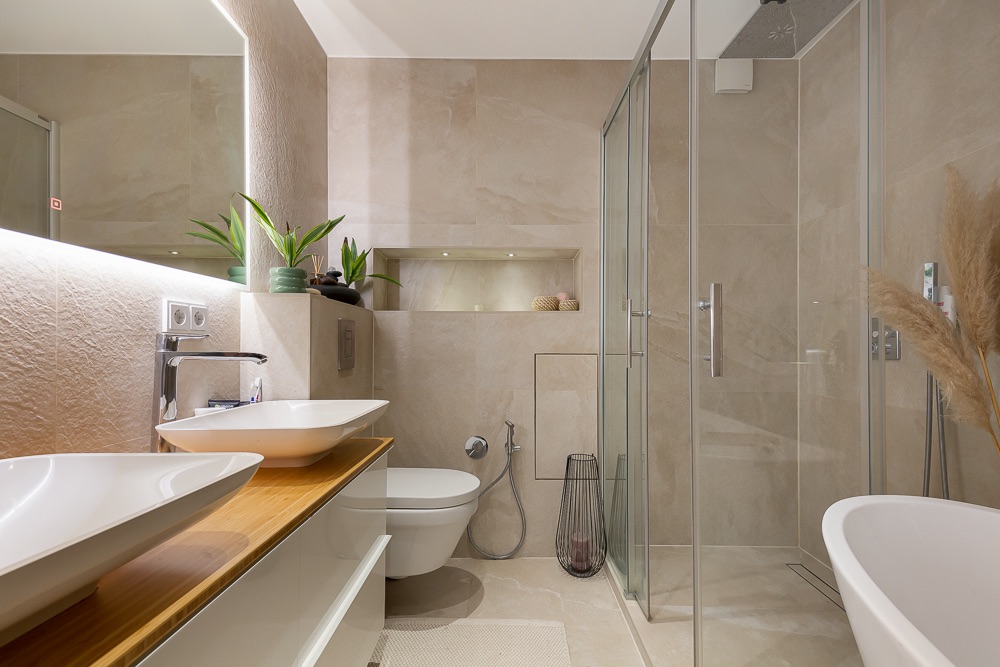 Modernes Badezimmer mit Doppelwaschbecken, Toilette, Dusche, Badewanne und Pflanzen.