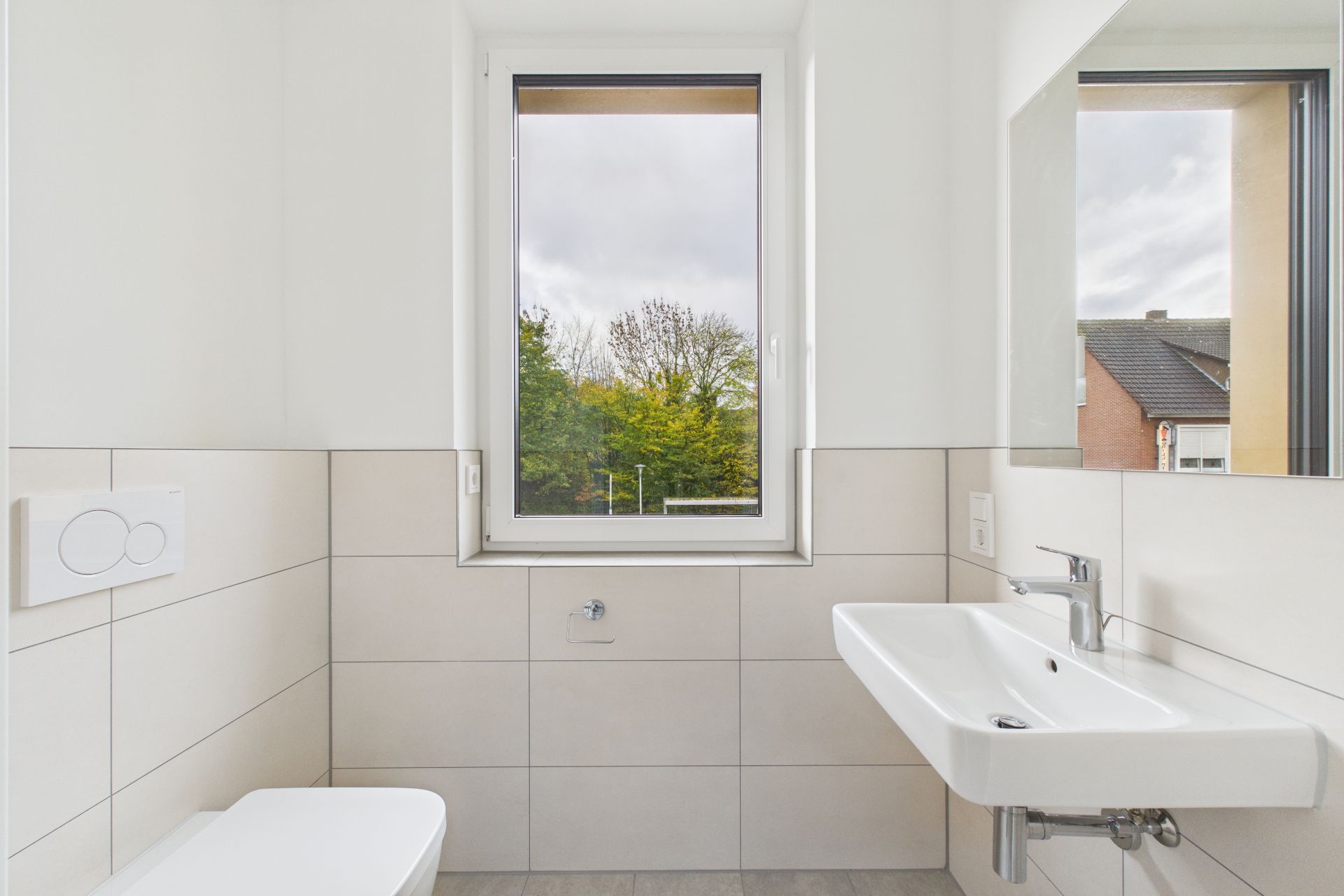 Modernes Badezimmer mit Fenster, Waschbecken, Spiegel und Toilette.