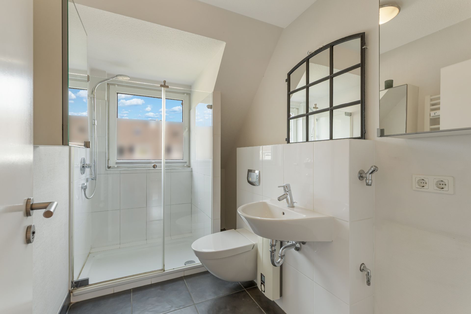 Modernes Badezimmer mit Dusche, WC, Waschbecken und großem Fenster.