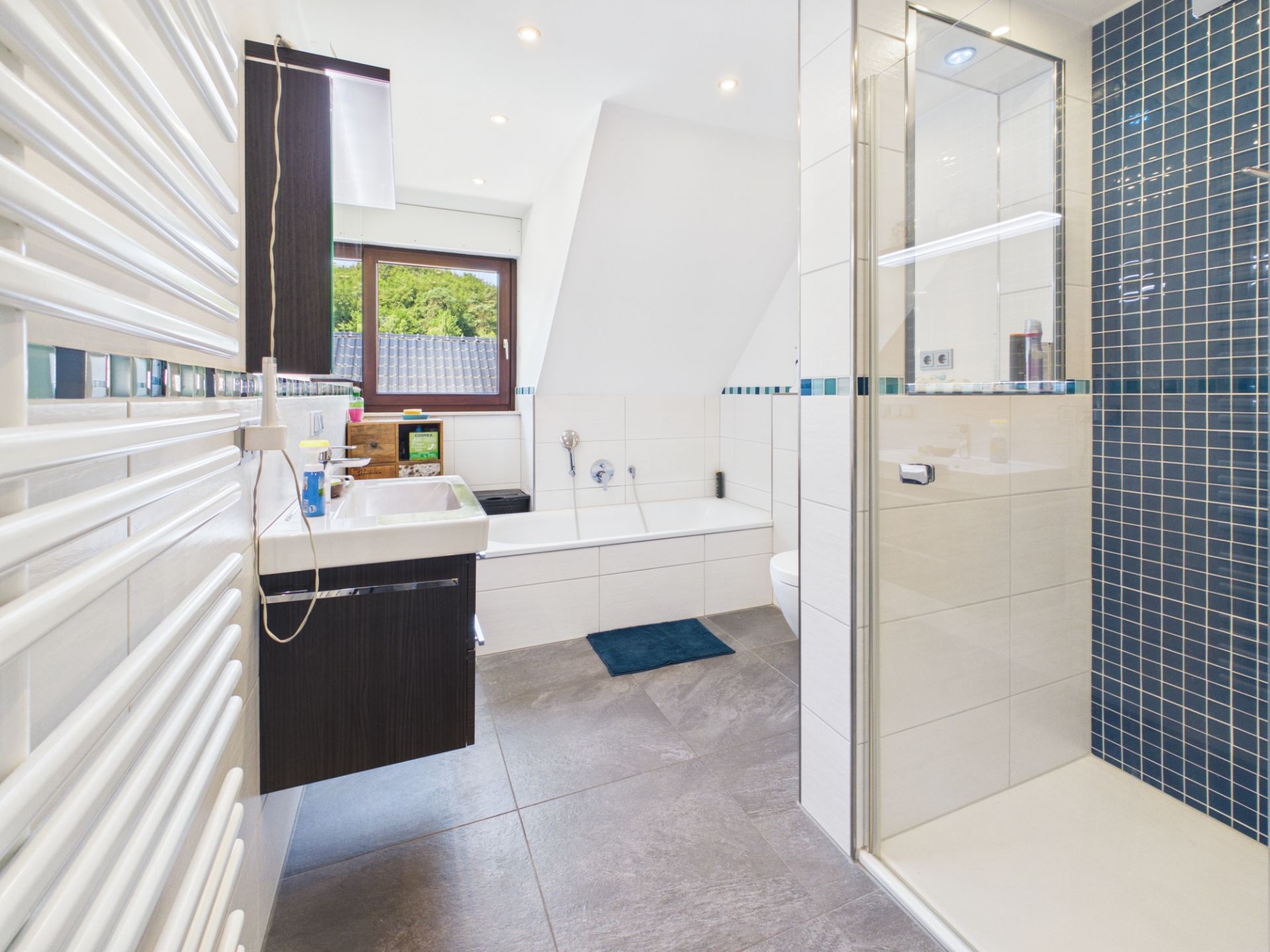 Modernes Badezimmer mit Dusche, Badewanne, Waschbecken und Fenster.