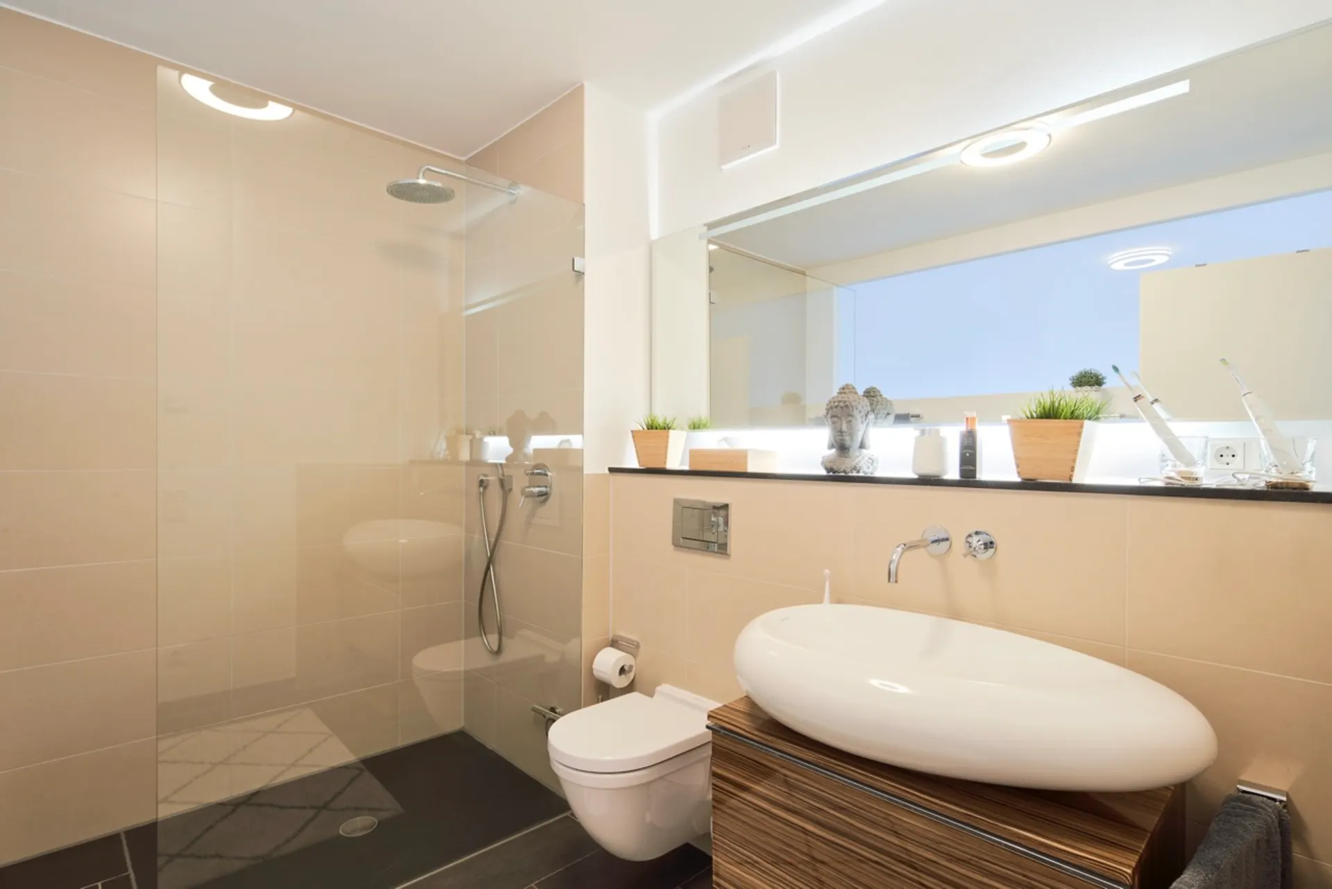 Modernes Badezimmer mit großer Dusche, Wandtoilette und Waschbecken vor großem Spiegel.