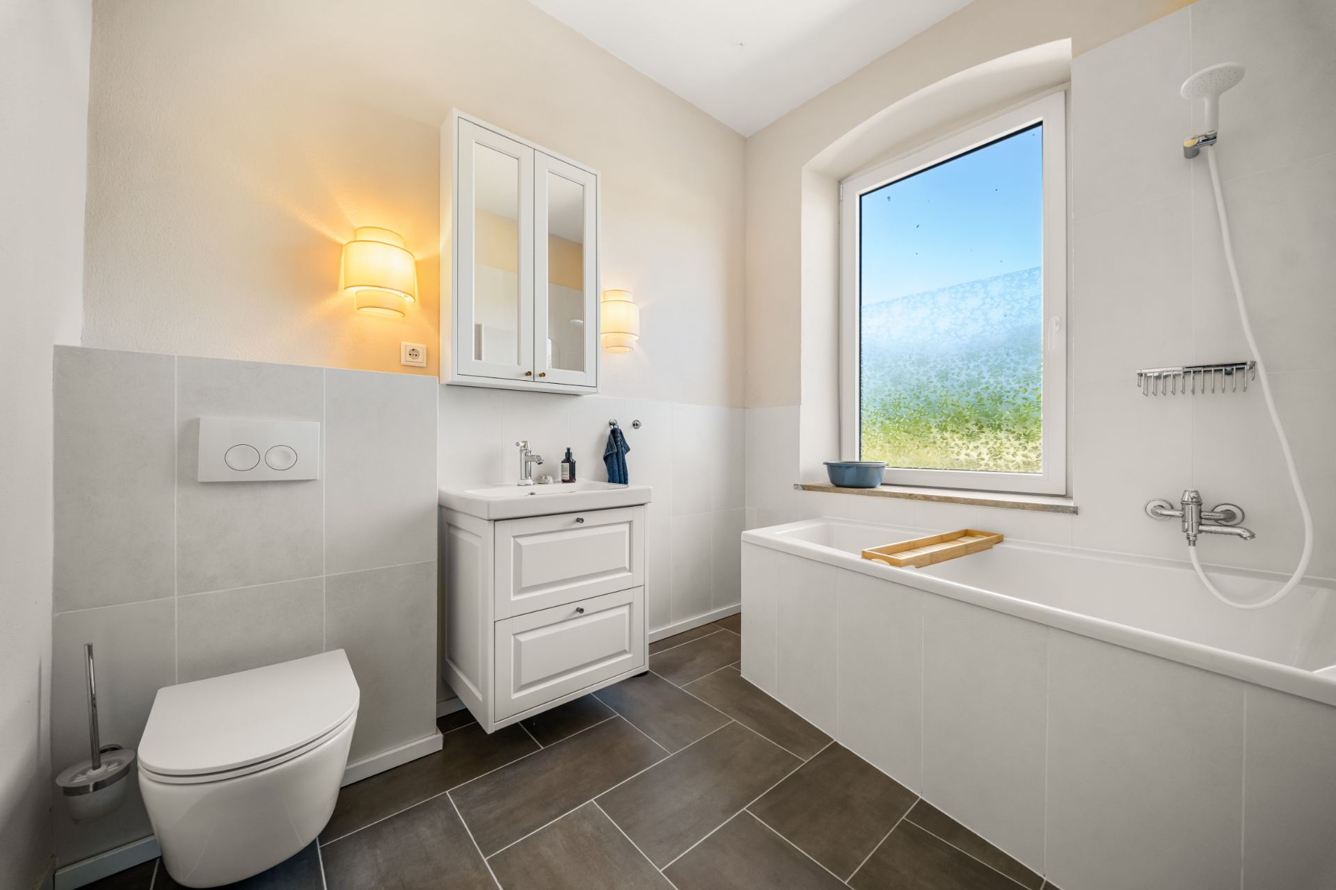 Modernes Badezimmer mit Badewanne, Waschbecken, Spiegel und Fenster.