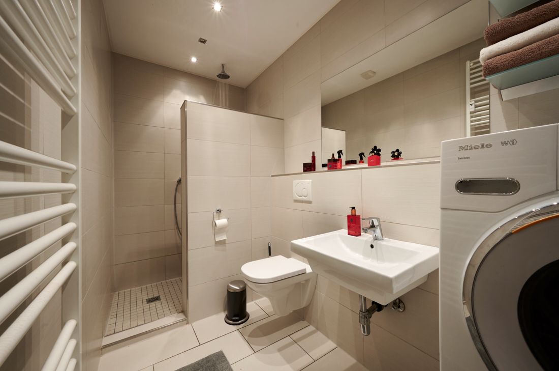Modernes Badezimmer mit Dusche, Waschbecken, Toilette und Waschmaschine.