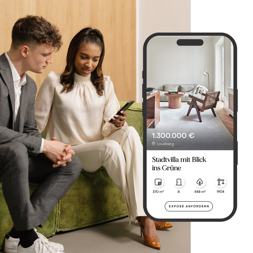 Zwei Personen sitzen auf grünem Sofa, halten ein Smartphone. Daneben Handy mit Wohnungsanzeige.