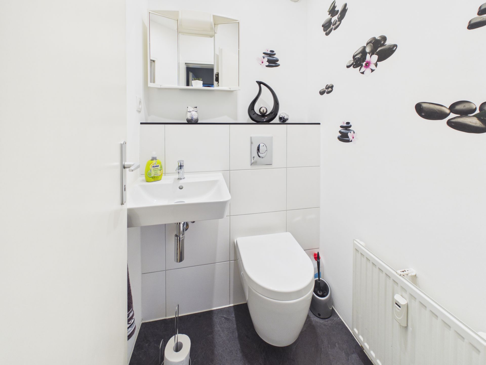 Kleines Badezimmer mit WC, Waschbecken, Spiegel und Wanddekoration aus Steinen.