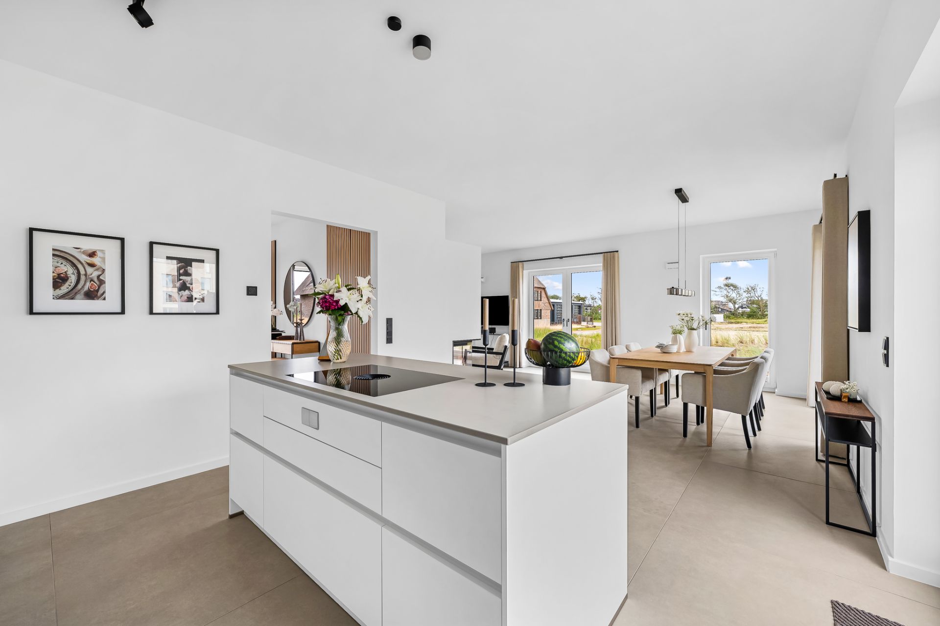 Moderne, helle Küche mit Kochinsel und offenem Übergang zum Ess- und Wohnzimmer.
