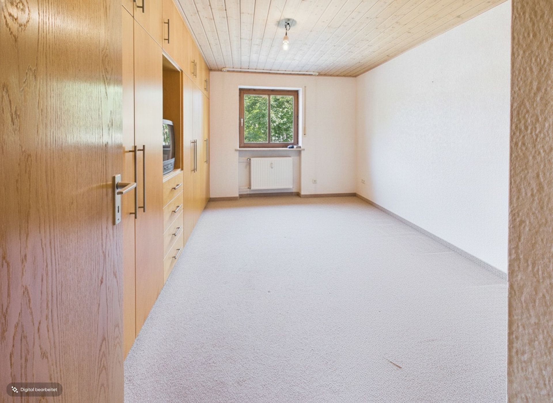 Helles, leeres Zimmer mit Teppichboden, Holzdecke, Einbauschrank und Fenster mit Blick ins Grüne.