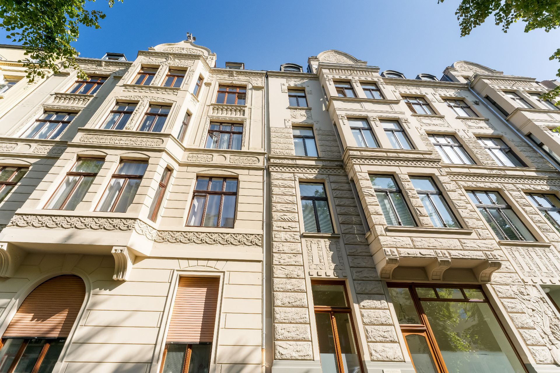 Fassade eines mehrstöckigen Altbauwohnhauses mit großen Fenstern und Stuckverzierungen.