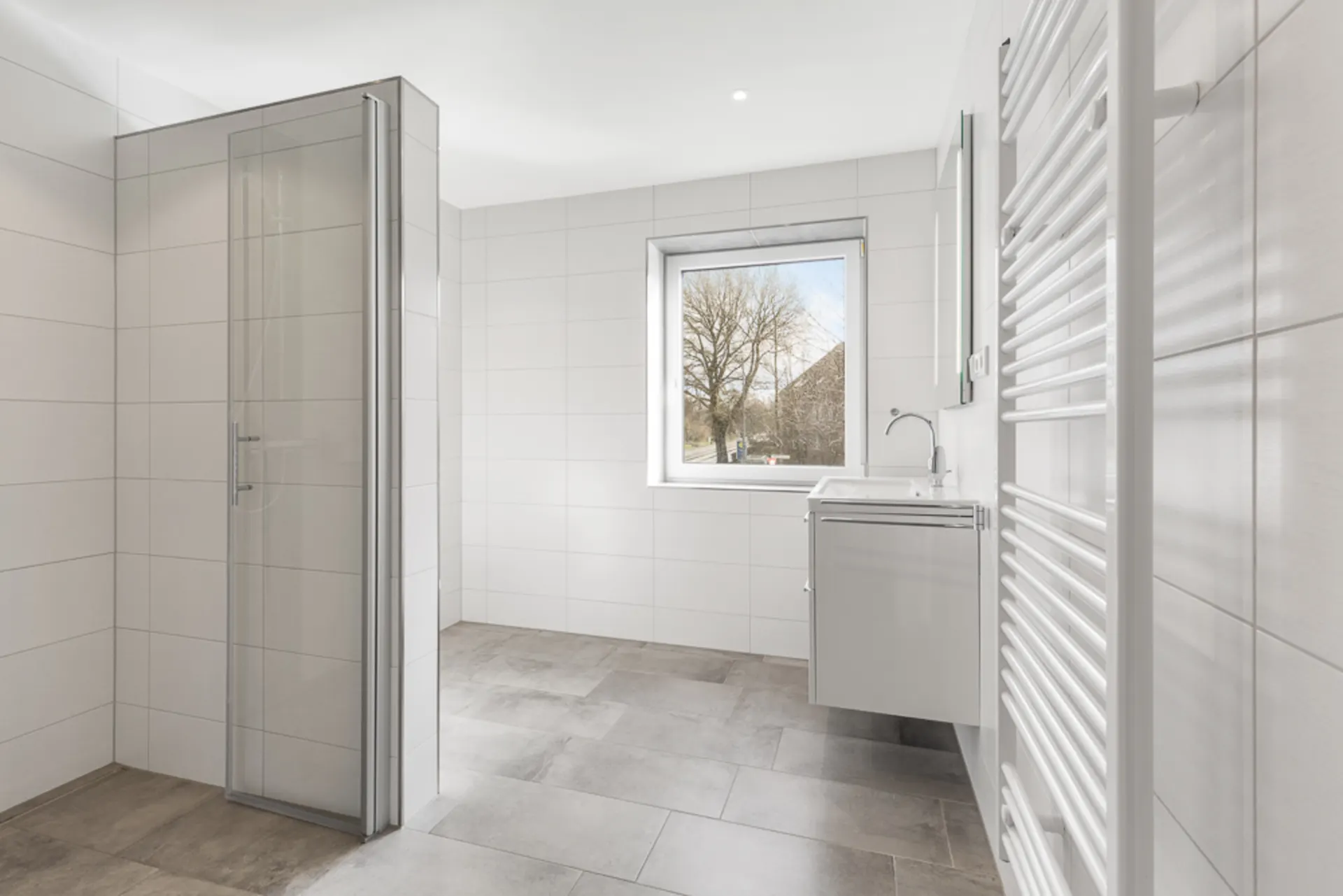 Helles, modernes Badezimmer mit Dusche, Fenster, Waschbecken und Handtuchheizkörper.
