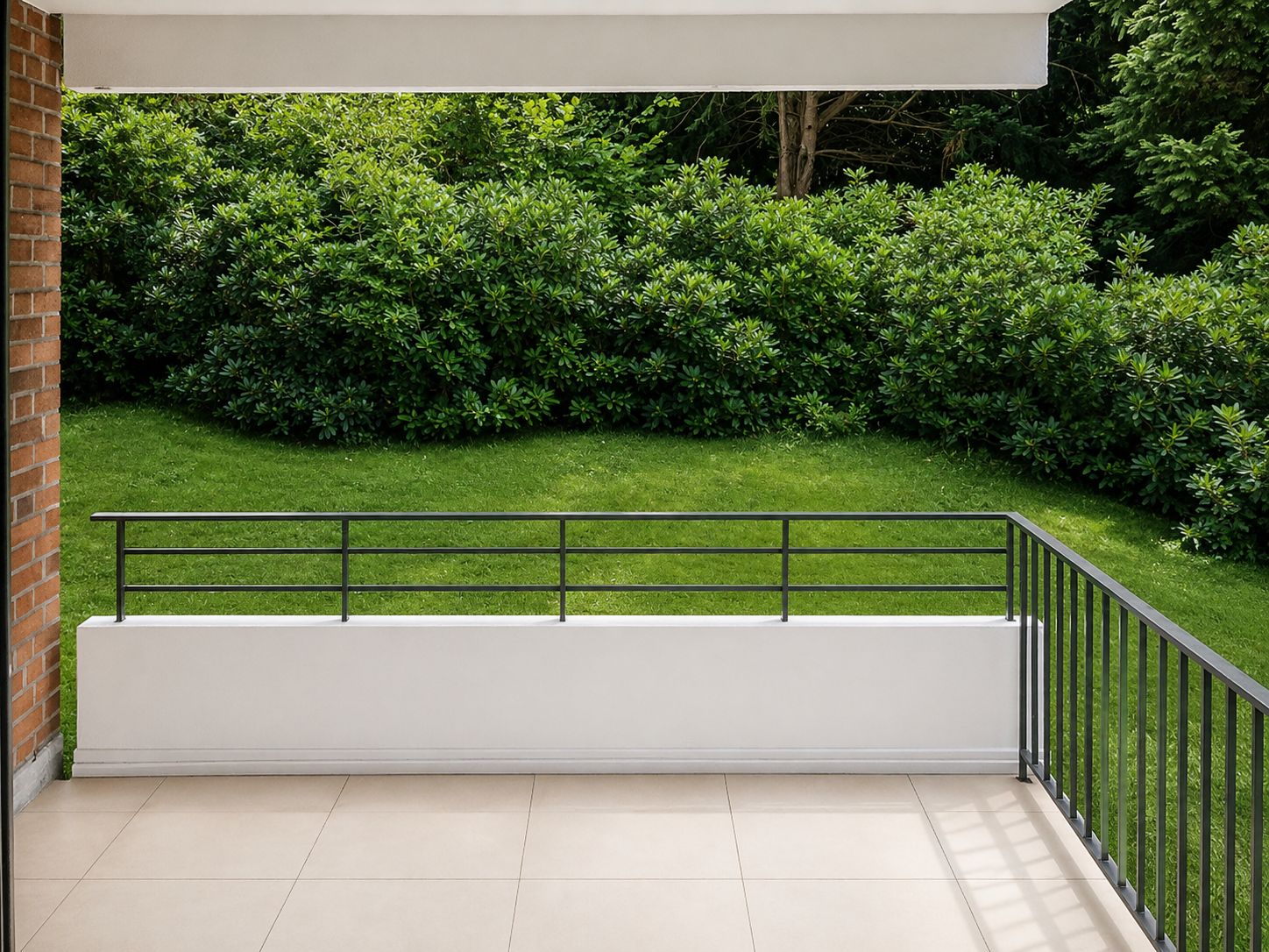 Blick von einer gefliesten Terrasse mit Geländer auf einen grünen Garten mit Büschen.