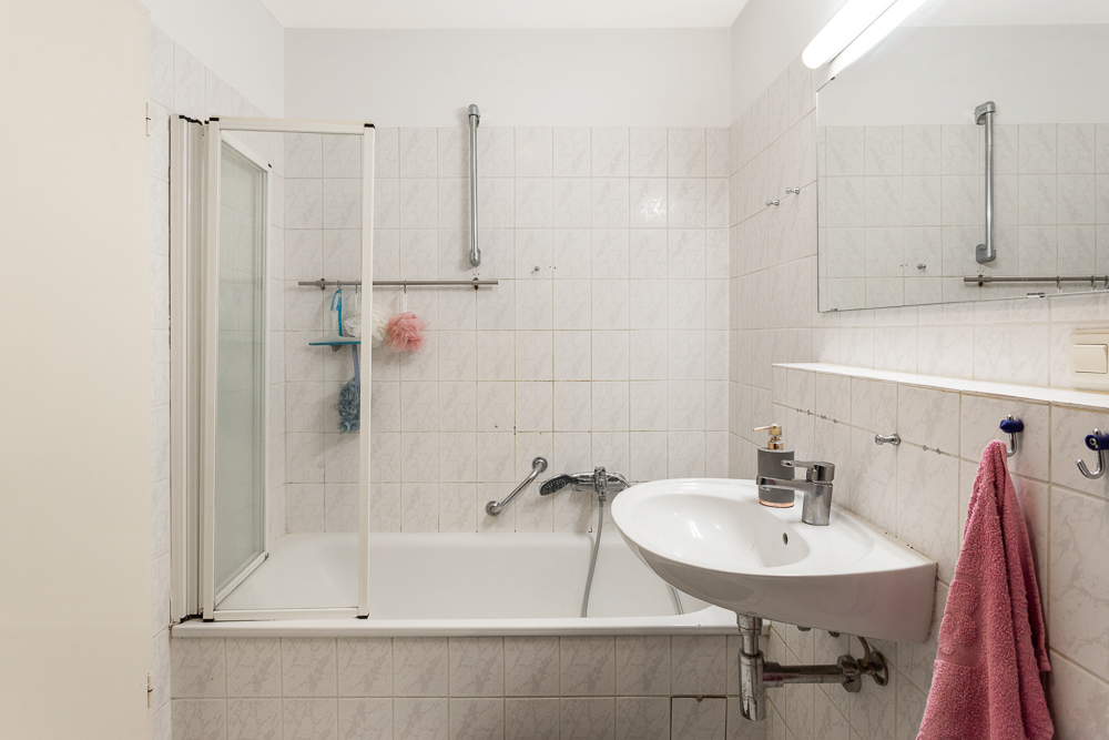 Kleines Badezimmer mit Badewanne, Waschbecken, Spiegel und Handtuch an der Wand.