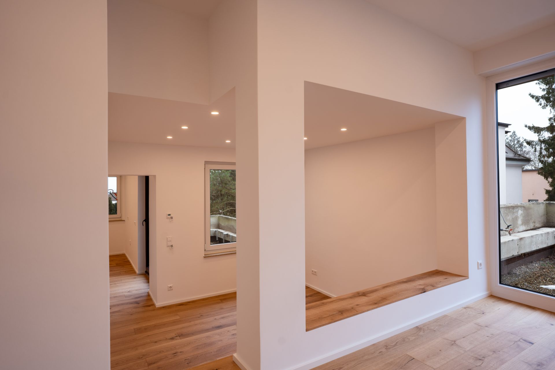 Modernes, helles Zimmer mit Holzboden, großen Fenstern und offenem Schnitt.