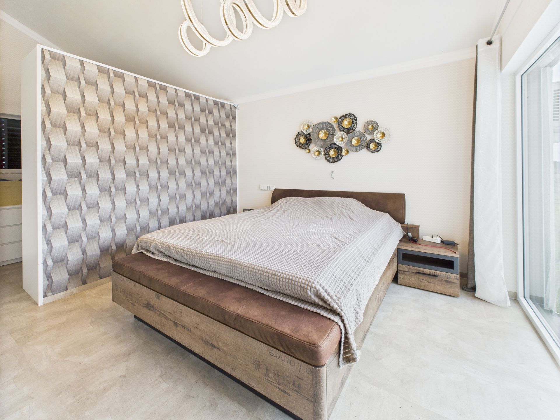 Modernes Schlafzimmer mit großem Bett, Nachttisch und geometrischer Mustertapete.