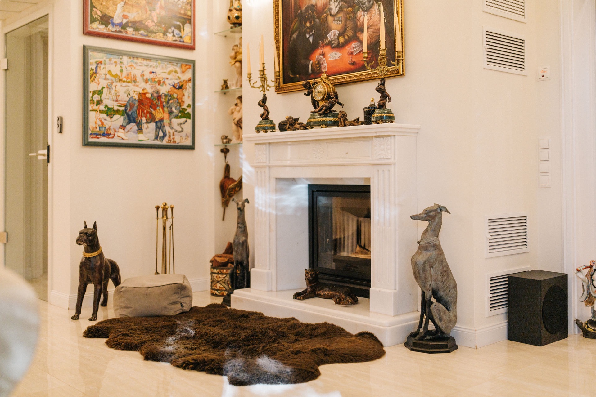 Wohnzimmer mit Kamin, Hundestatuen, Fellteppich und Gemälden an der Wand.