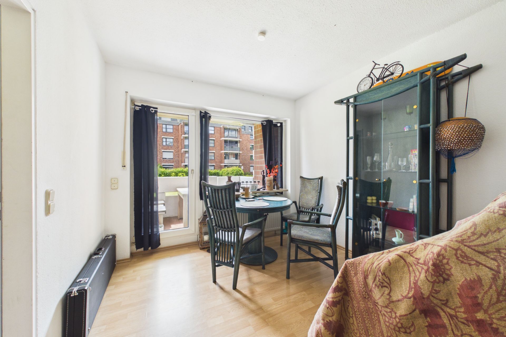 Helles Esszimmer mit Glastisch, vier Stühlen, Glasvitrine und Zugang zu einem Balkon.