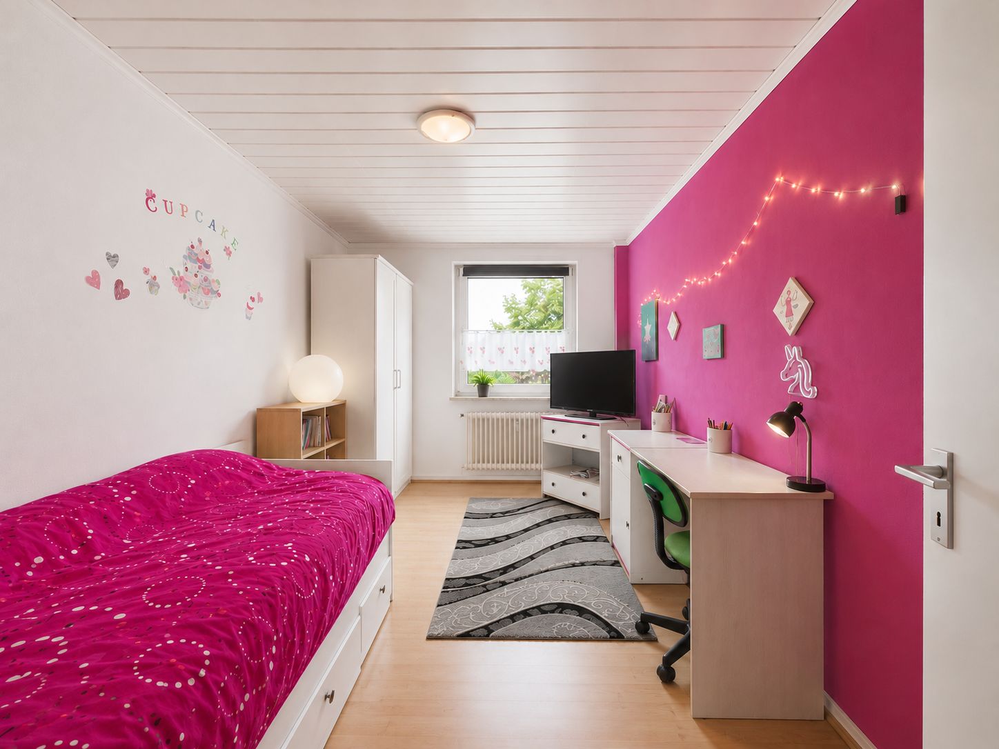 Helles Kinderzimmer mit pinker Wand, Bett, Schreibtisch, Fernseher und Dekoration.