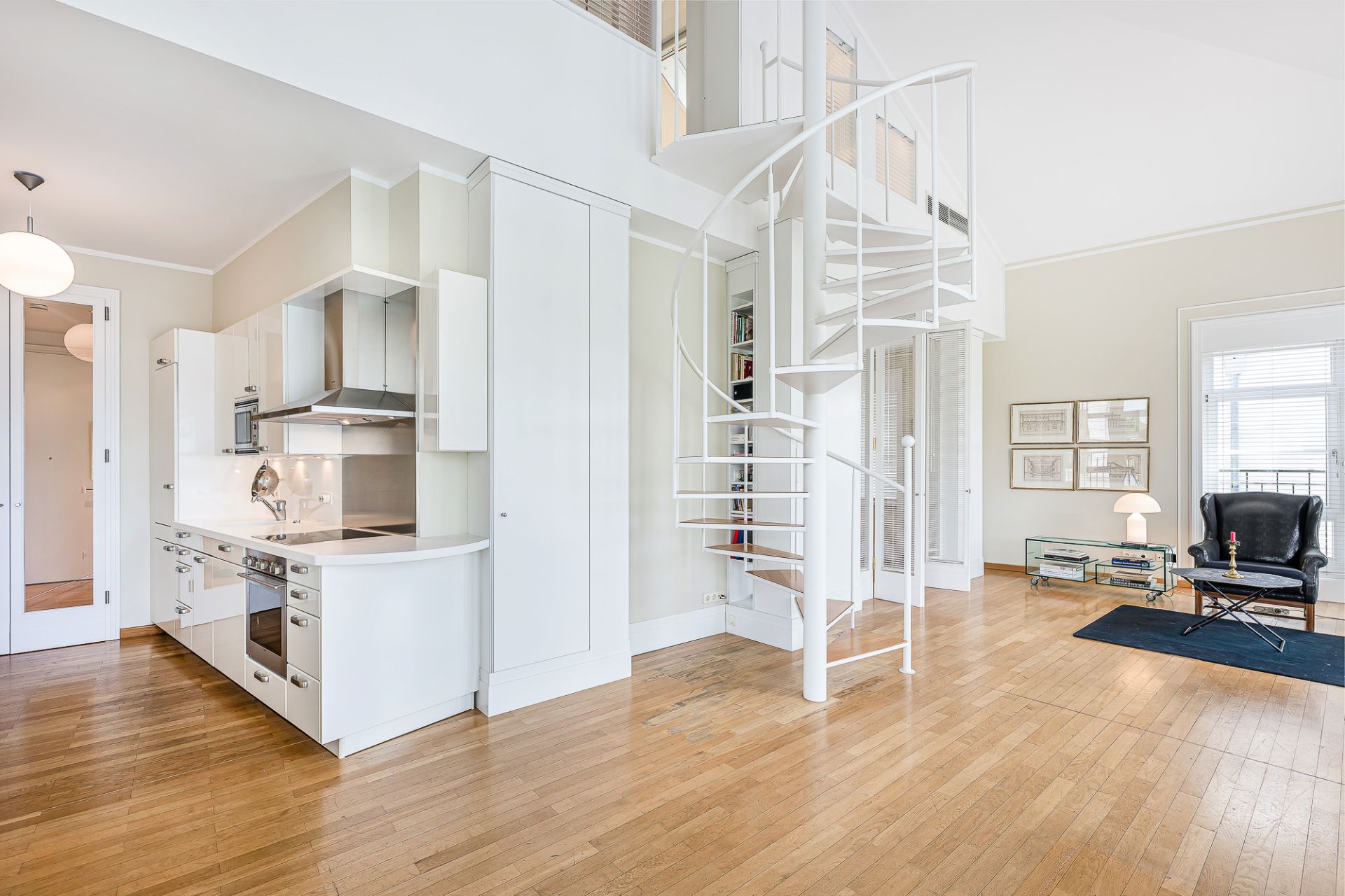 Modernes Wohnzimmer mit offener Küche, Holzfußboden und weißer Wendeltreppe.