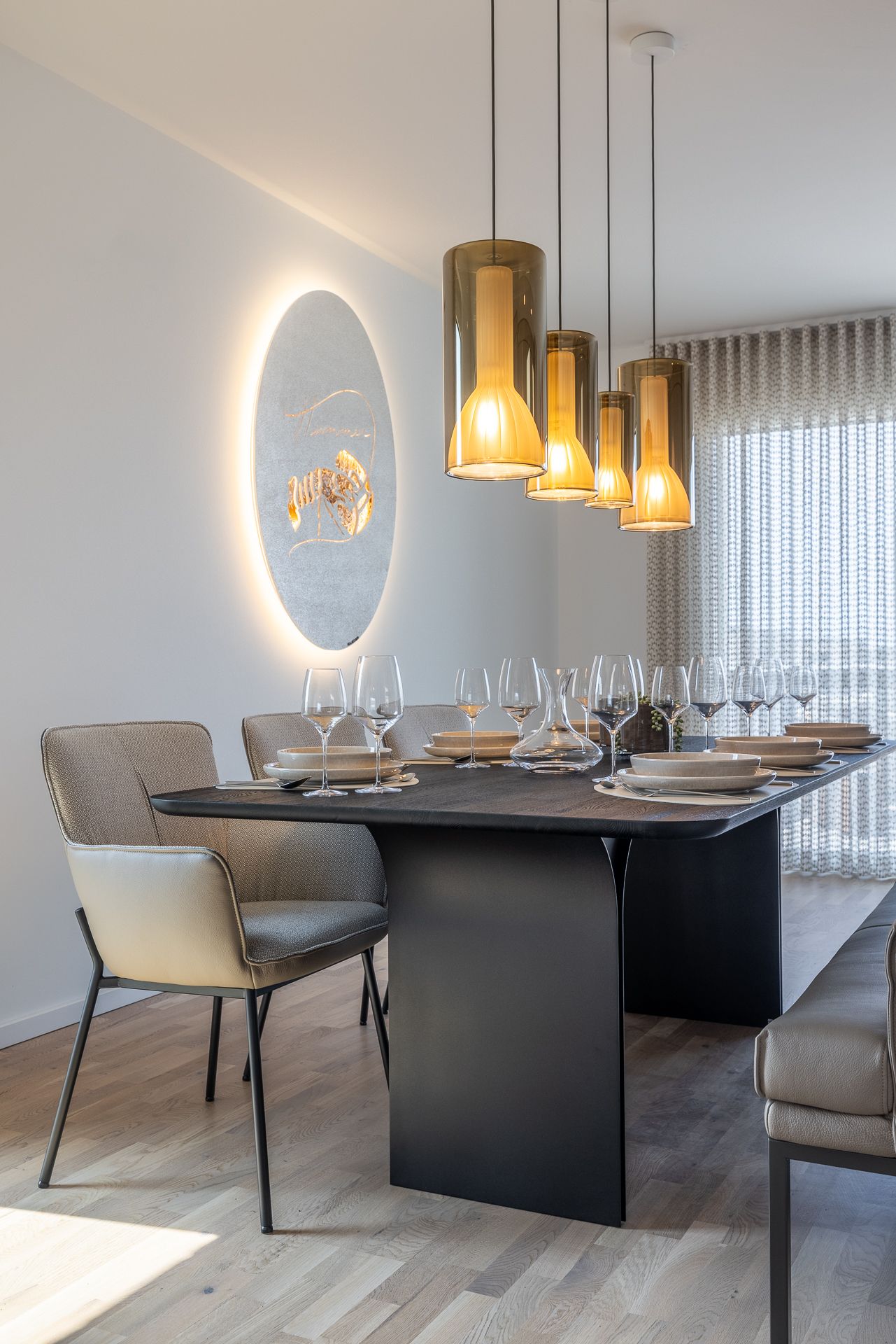 Modernes Esszimmer mit schwarzem Tisch, gedecktem Geschirr und Hängelampen.