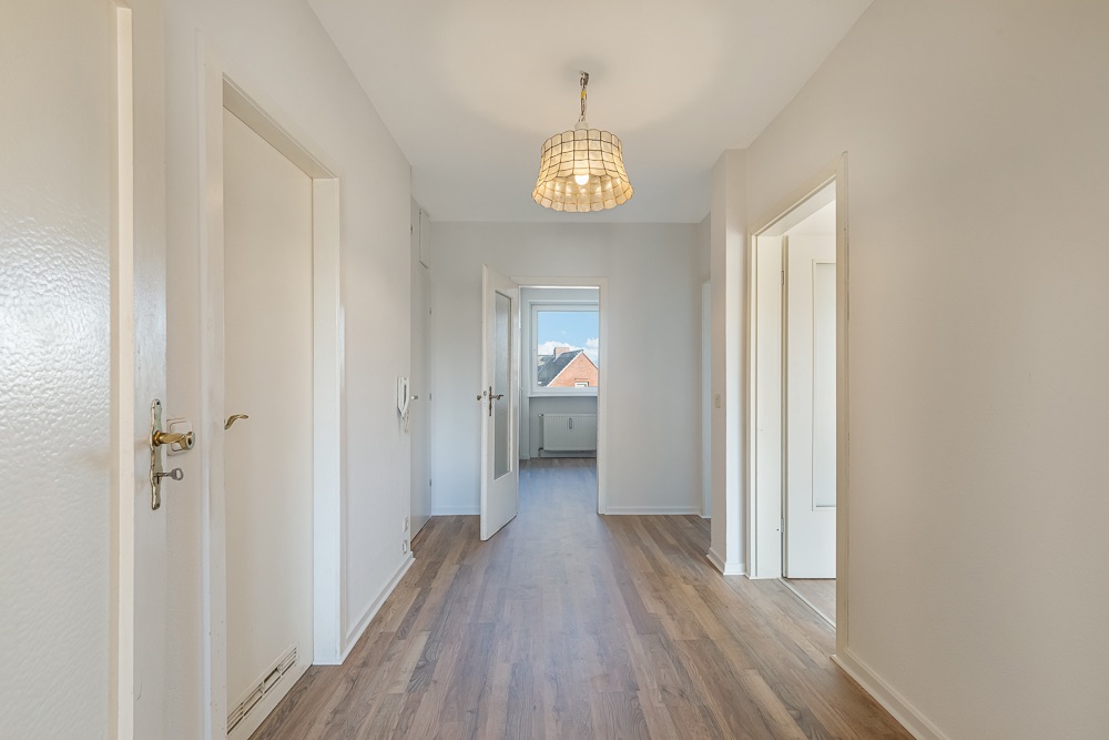 Heller Flur mit Holzboden, mehreren Türen und einer Deckenlampe.