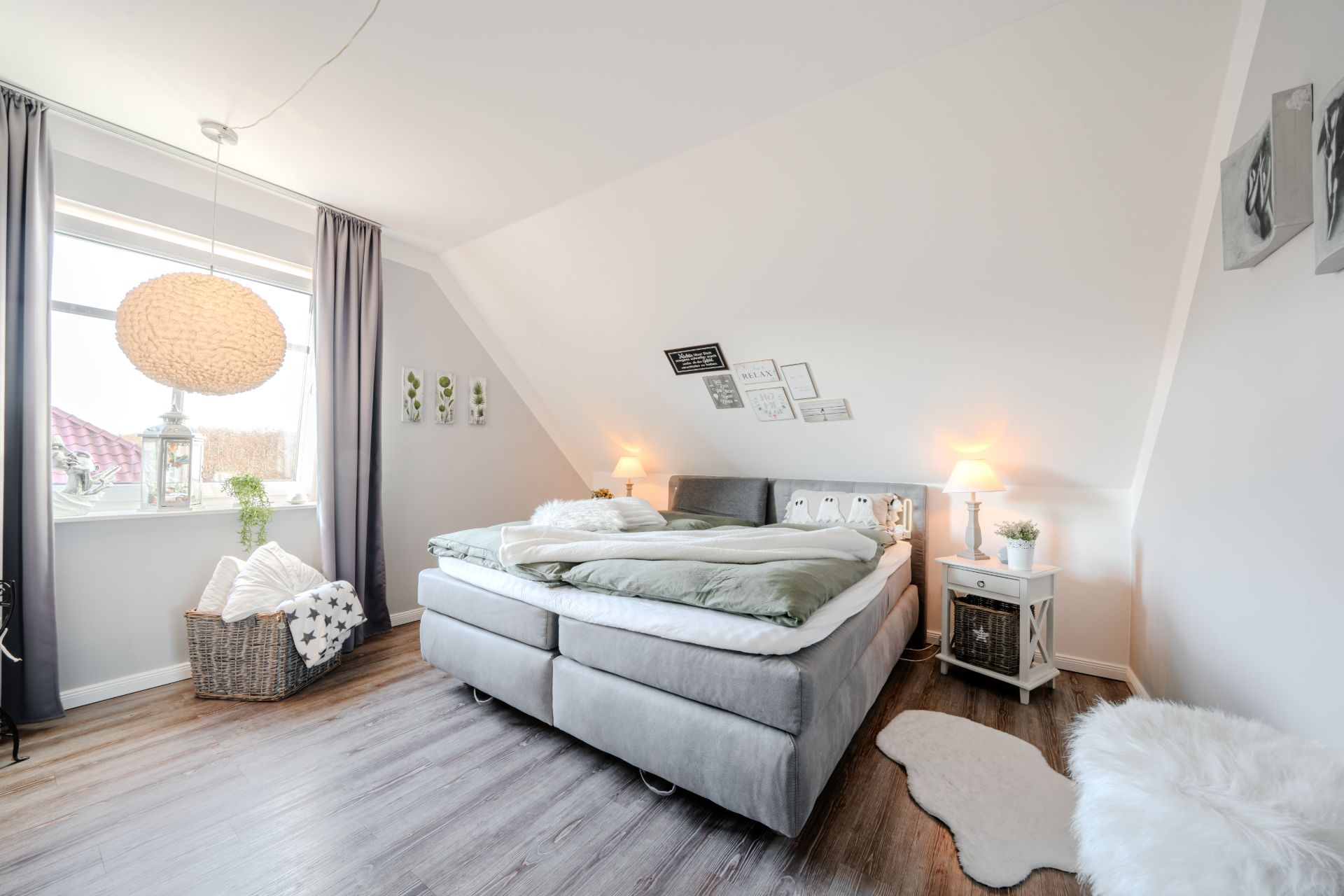 Helles Schlafzimmer mit Doppelbett, Nachttischen, Fenstern und Dekoration auf weißen Wänden.