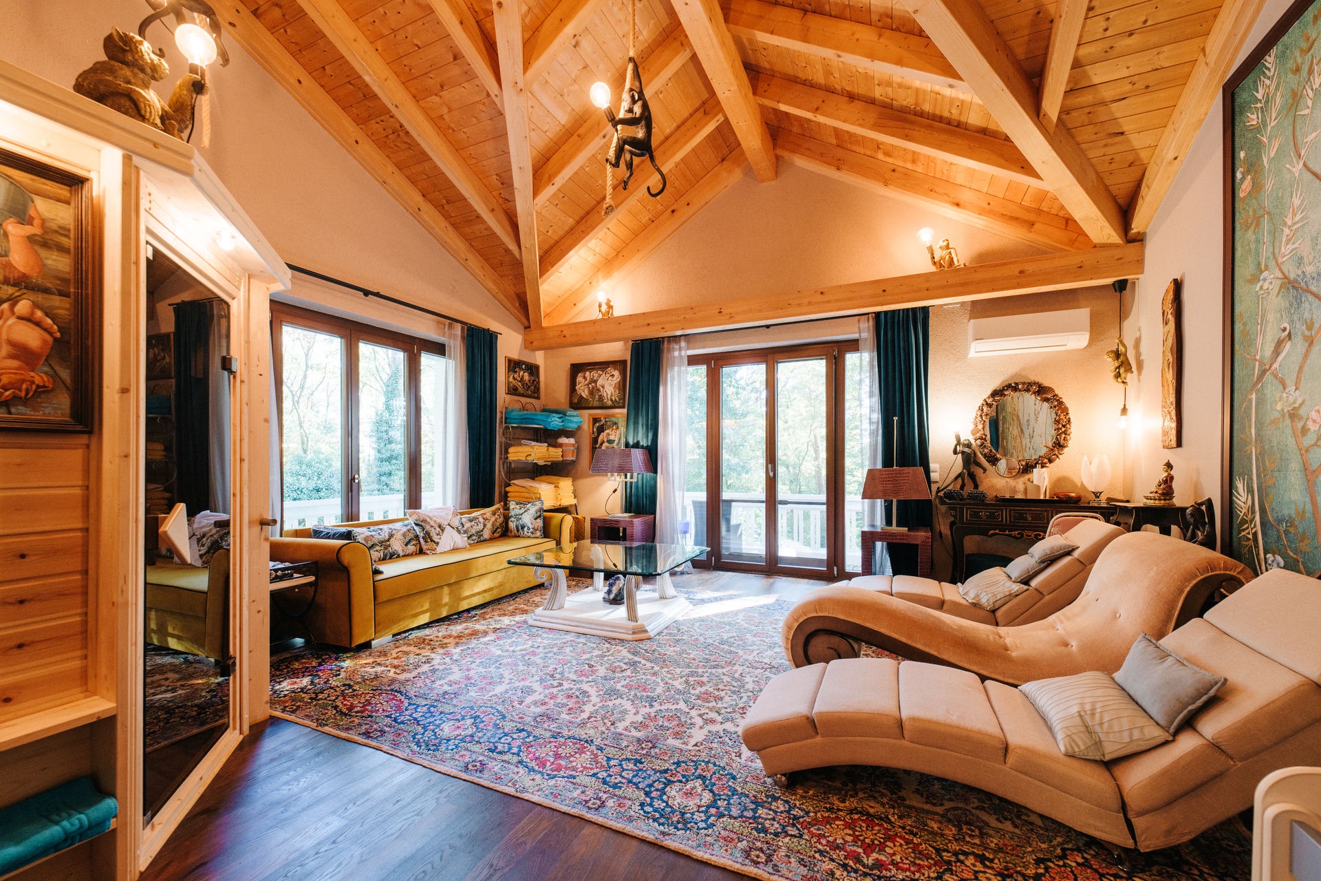 Helles Wohnzimmer mit Holzbalkendecke, großen Fenstern, Teppich und gemütlichen Sofas.